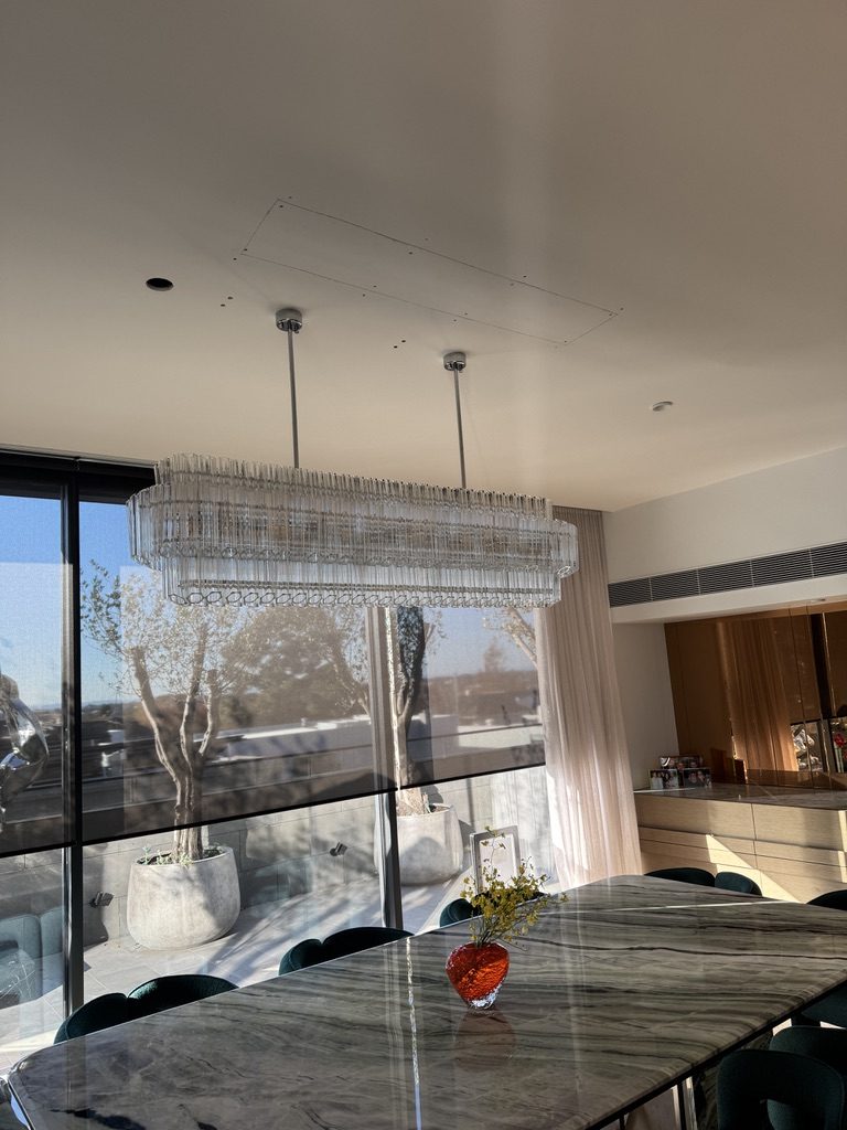 Glass-rod linear chandelier over a marble dining table