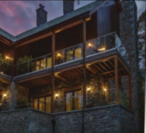 Multi-level home with glass balustrades lit at dusk