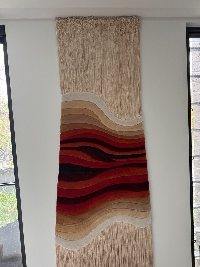 Tall wall hanging with red and tan wave bands and cream fringe