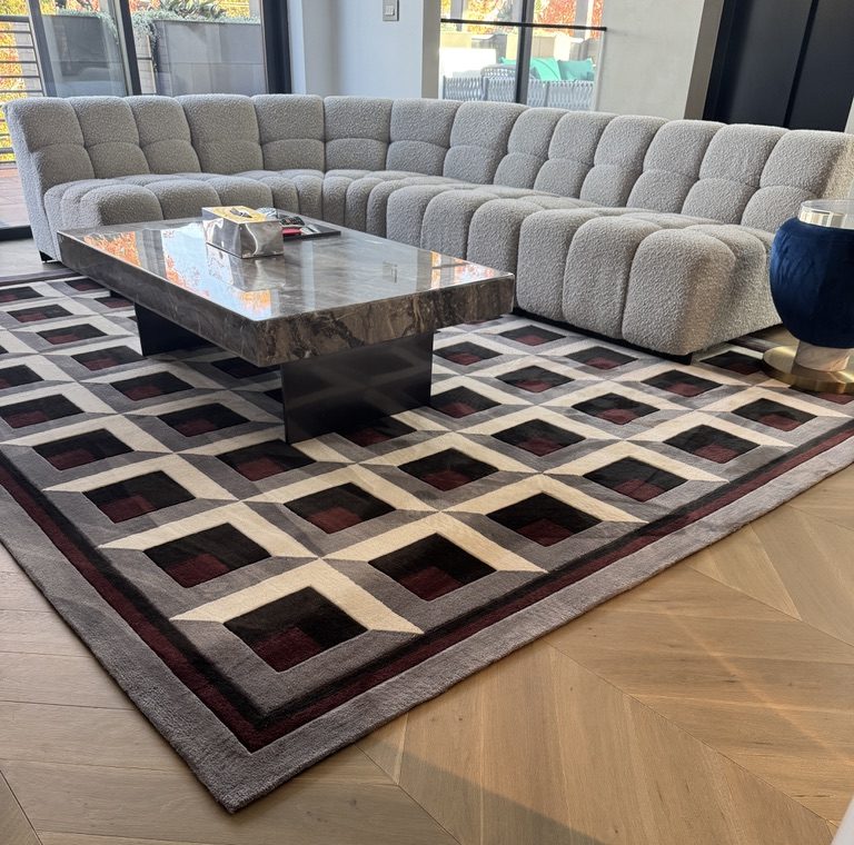 Geometric wool rug under a boucle modular sofa and stone coffee table