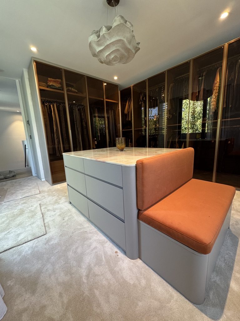 Walk-in robe with glass wardrobes and upholstered bench